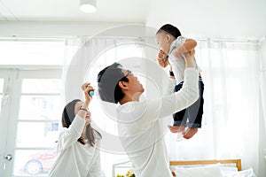 Asian father and mother lifting their little own son up flying in the air with laughter