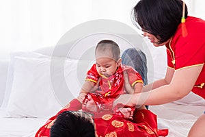 Asian father  mother playing with son toddler boy on bed at home  Chinese family in red Chinese costume give envelope to baby 