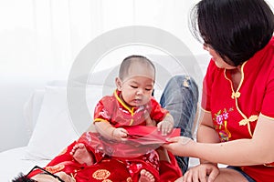 Asian father  mother playing with son toddler boy on bed at home  Chinese family in red Chinese costume give envelope to baby 