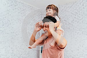 Asian father playing with daughter at home