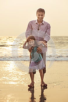 Asian father playing and having with his daughter on beach