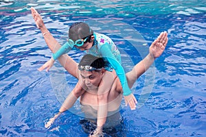 Asian father playing with his daughter in swimming pool