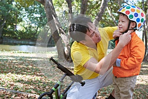 Asian father put helmet on cute little 3 years old toddler boy child, Dad and son having fun with balance bike run bike on