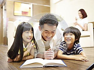 Asian father reading book telling story to two children