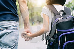 Asian father`s hand lead his girl child in summer park go to sch