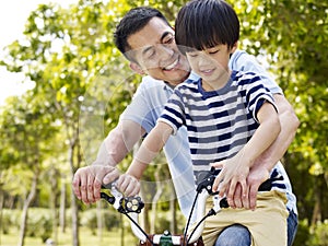 Asian father and son enjoying biking outdoors