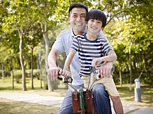 Asian father and son enjoying biking outdoors