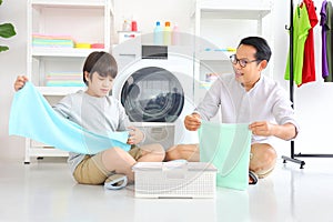 Asian father and  son help each other doing laundry together for daily chores