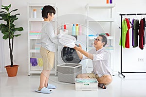 Asian father and son help each other doing laundry together for daily chores