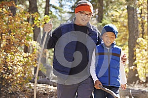 Asian father and son hiking in a forest, embracing