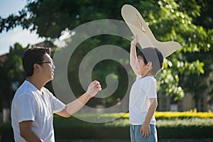 Asian father and son playing cardboard airplane together