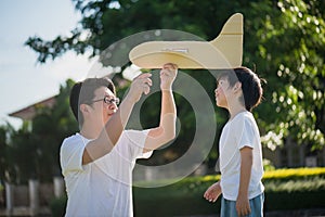 Asian father and son playing cardboard airplane together