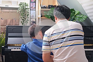 Asian Father and son playing piano at home, Children and Music