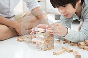 Asian father with son plays wooden bloack game at home