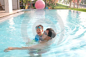 Asian Father and son takes a swimming lesson at swimming pool, Cute little Asian toddler boy child learning to swim with his dad