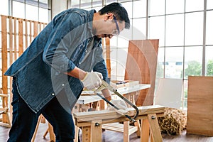 Asian father and son work as a woodworker or carpenter, Father wears safety goggles and saw a wooden plank with hacksaw carefully