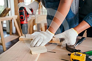 Asian father and son work as a woodworker or carpenters. Close up hands of the father and his son drill holes in a wooden plank