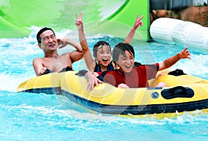 Asian father and sons having fun tubing at a waterpark photo