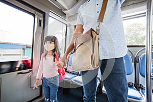 asian father taking his daughter to school by riding bus public transport wearing a face mask
