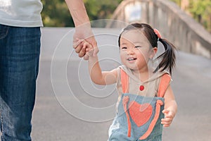 Asian father walking with daughter in park, Parents hold the baby\'s hands