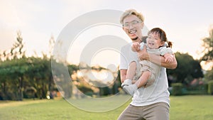 Asian father walking with daughter in park, Parents hold the baby\'s in his hand , Happy family in the park evening light.