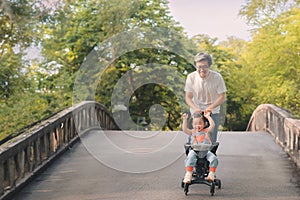 Asian father walking with daugther in stroller in park, Happy family concept