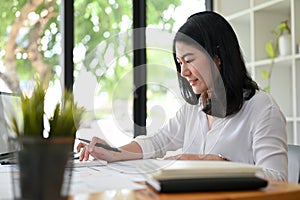 Asian female accountant concentrating while working on her sales accounts report