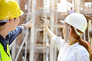Asian female architect planning a building plan with a male engineer at the construction site