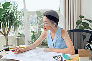 Asian female architect studying plans in office