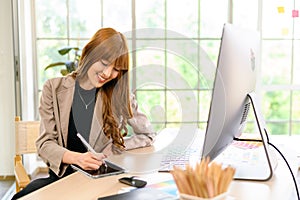 Asian female artist drawing something on graphic tablet. graphic designer working at office