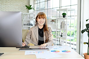 Asian female artist drawing something on graphic tablet. graphic designer working at office. Looking at camera