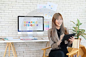 Asian female artist drawing something on graphic tablet. graphic designer working at office. Looking at camera