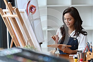 Asian female artist painting picture in her studio.