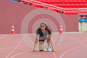 Asian female athlete at start block, ready for her speed running practice on the stadium track, epitomizing readiness