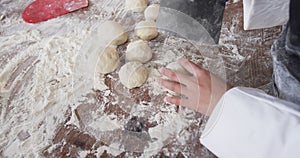 Asian female baker working in bakery kitchen, making rolls from dough in slow motion