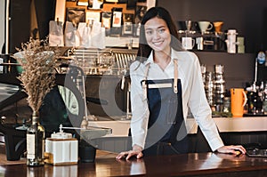 Asian female barista wear jean apron place her hand on counter b