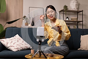 Asian Female Beauty Blogger Making Makeup Filming On Smartphone Indoors