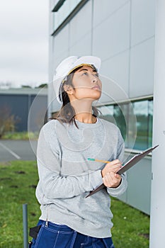 Asian female building inspector with clipboard outside building