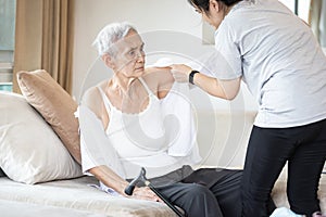 Asian female caregiver taking care of helping elderly patient get dressed,wearing clothes or undressing for senior mother,