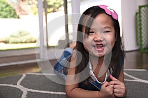 Asian female child lying on floor and smiling