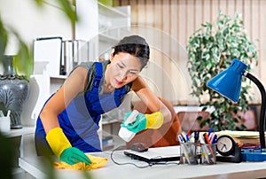 Asian female cleaning desk in office