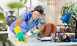 Asian female cleaning desk in office