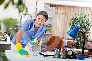 Asian female cleaning desk in office