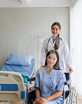 Asian female doctor cheered on a female patient in a wheelchair in her room