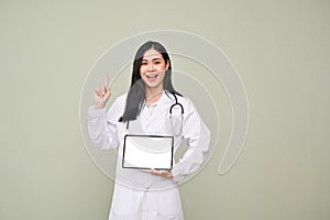 Asian female doctor holding tablet, pointing finger up, standing against grey background