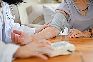 An Asian female doctor or nurse uses a blood pressure monitor to measure a patient`s blood pressure