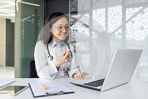 Asian female doctor providing remote consultation in modern clinic office environment