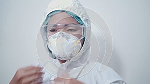 Asian female doctor put on ppe suit, personal protective equipments white medical suit, protective glasses, n95 mask, pandemic cov