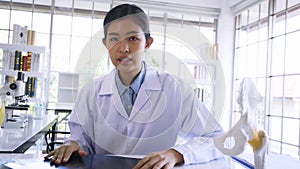 Asian female doctor sitting in hospital cabin reading and analyzing issue in lungs of patient with x-ray film in lab