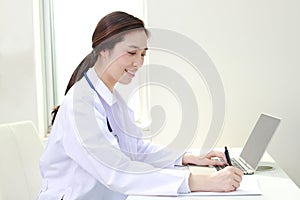 Asian female doctor sitting in office Write a record of the patient`s treatment.